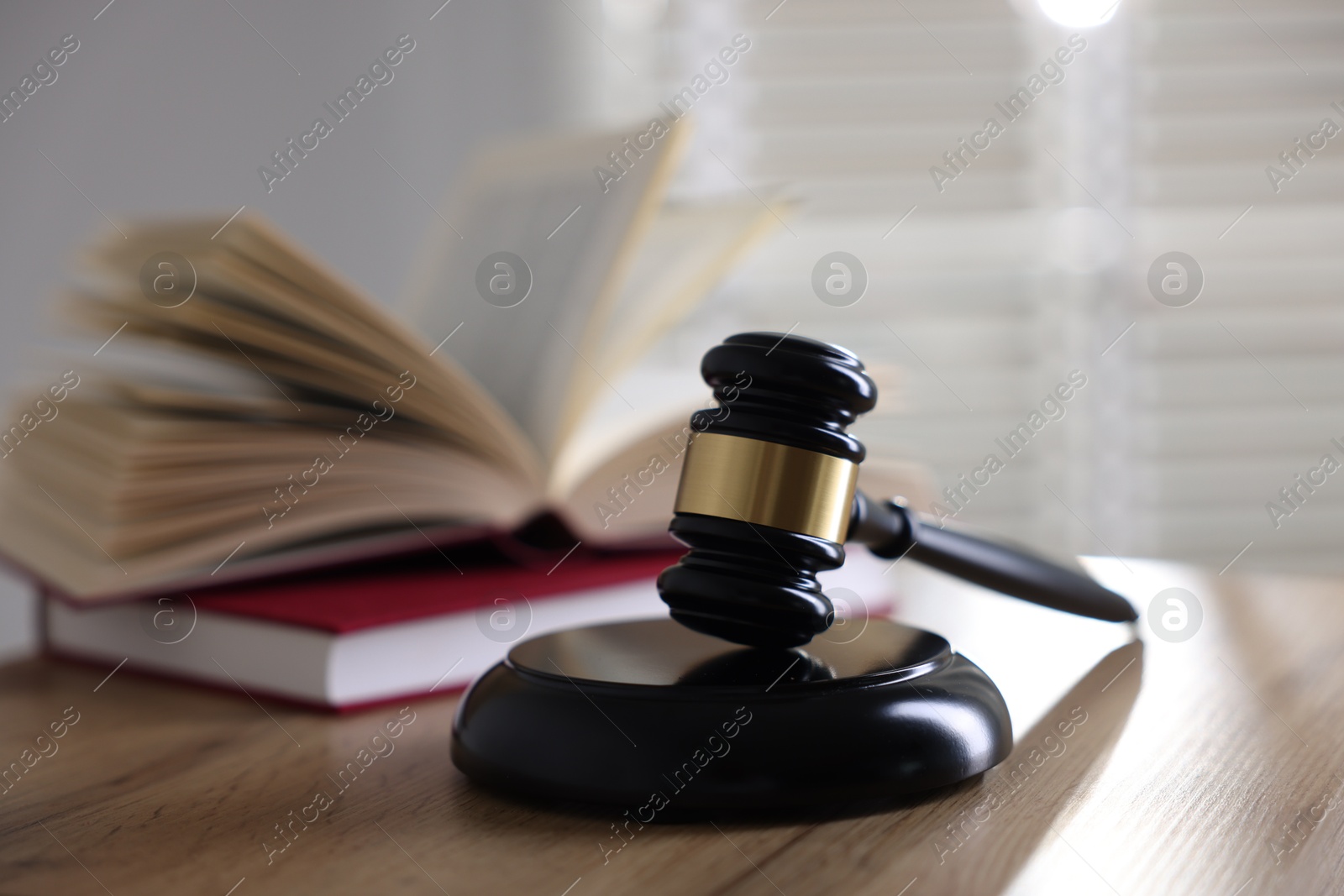 Photo of Judge's gavel and books on wooden table indoors, selective focus