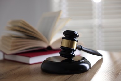 Photo of Judge's gavel and books on wooden table indoors, selective focus