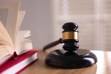 Photo of Judge's gavel and books on wooden table indoors, closeup