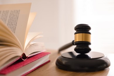 Photo of Judge's gavel and books on wooden table indoors, closeup