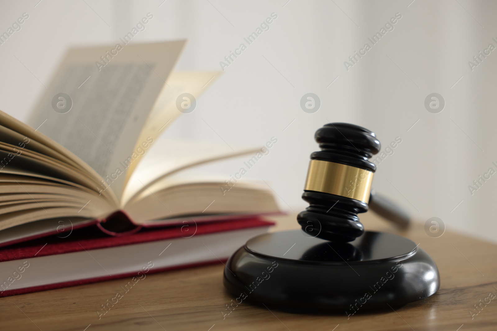 Photo of Judge's gavel and books on wooden table indoors, selective focus