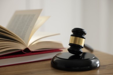 Photo of Judge's gavel and books on wooden table indoors, selective focus