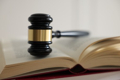 Photo of Judge's gavel on book against light background, closeup