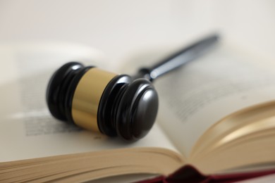 Photo of Judge's gavel on book against light background, closeup