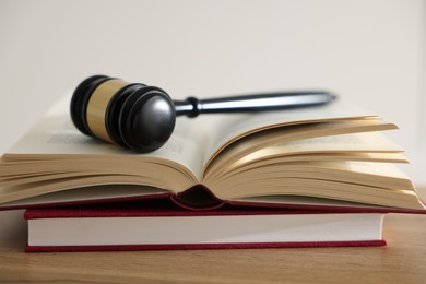 Photo of Judge's gavel and books on wooden table indoors, closeup