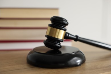 Photo of Judge's gavel and books on wooden table indoors, selective focus