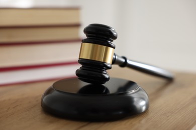 Photo of Judge's gavel and books on wooden table indoors, selective focus