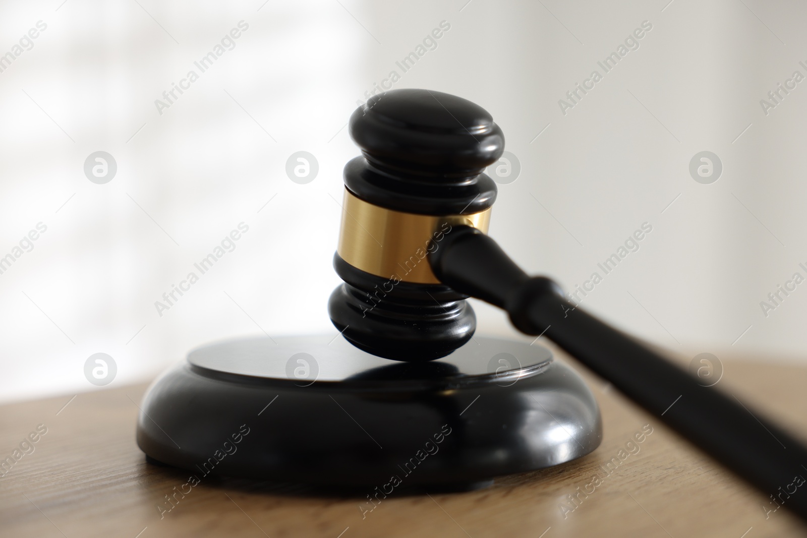Photo of Judge's gavel on wooden table against light background, closeup
