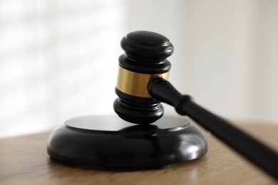 Photo of Judge's gavel on wooden table against light background, closeup