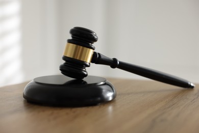 Photo of Judge's gavel on wooden table against light background, closeup