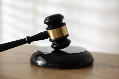 Photo of Judge's gavel on wooden table against light background, closeup
