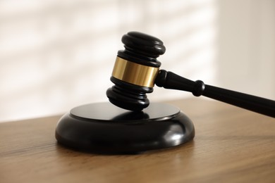 Photo of Judge's gavel on wooden table against light background, closeup