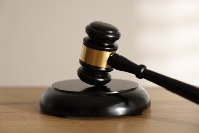Photo of Judge's gavel on wooden table against light background, closeup