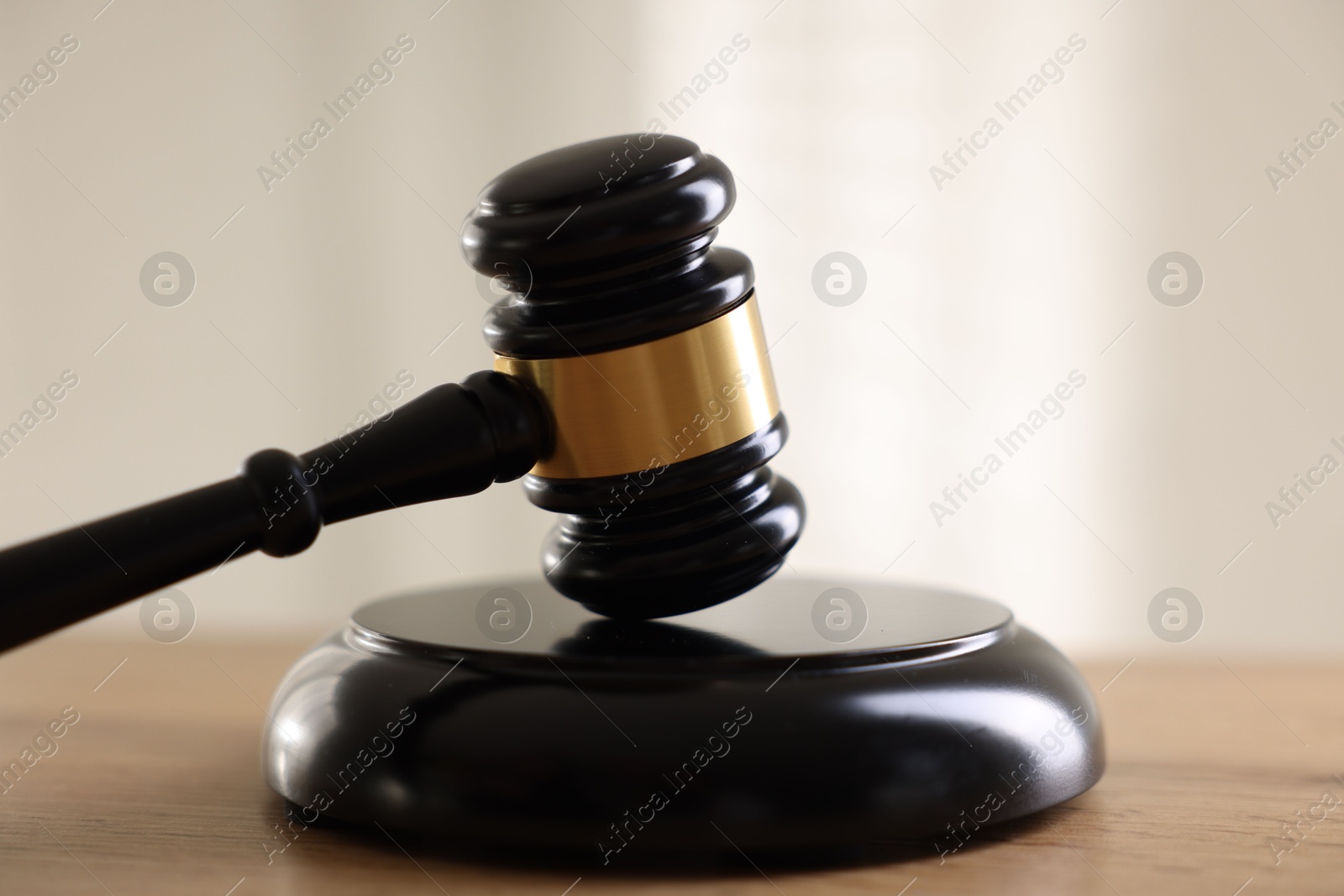 Photo of Judge's gavel on wooden table against light background, closeup