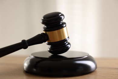 Photo of Judge's gavel on wooden table against light background, closeup