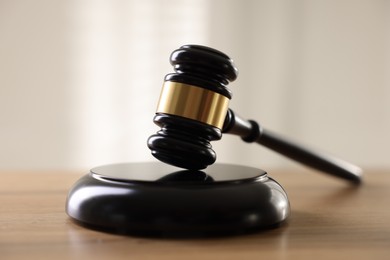 Photo of Judge's gavel on wooden table against light background, closeup
