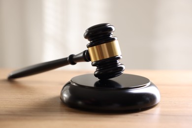 Photo of Judge's gavel on wooden table against light background, closeup