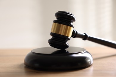 Photo of Judge's gavel on wooden table against light background, closeup