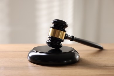 Photo of Judge's gavel on wooden table against light background, closeup