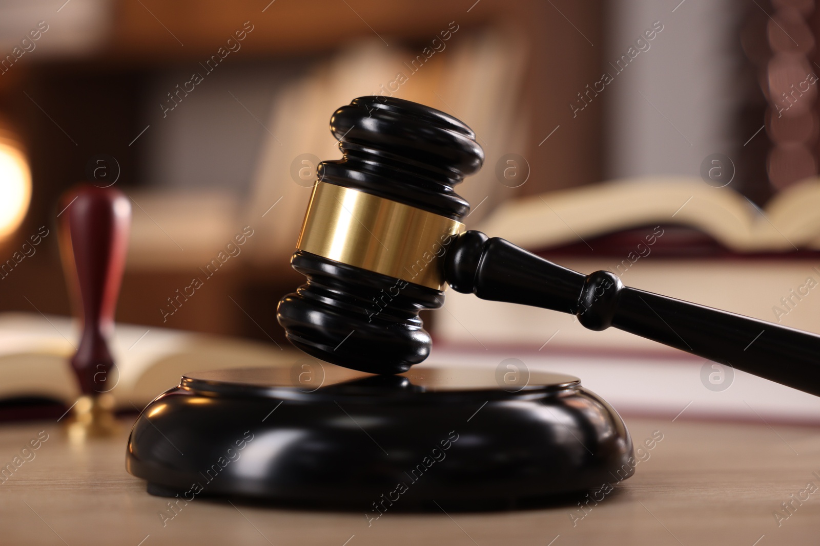 Photo of Judge's gavel and books on wooden table indoors, selective focus