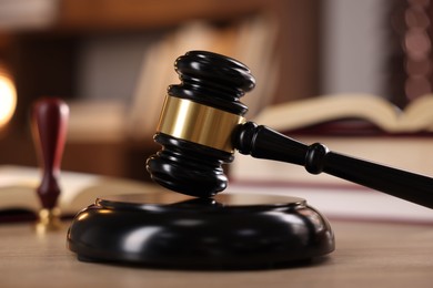 Photo of Judge's gavel and books on wooden table indoors, selective focus