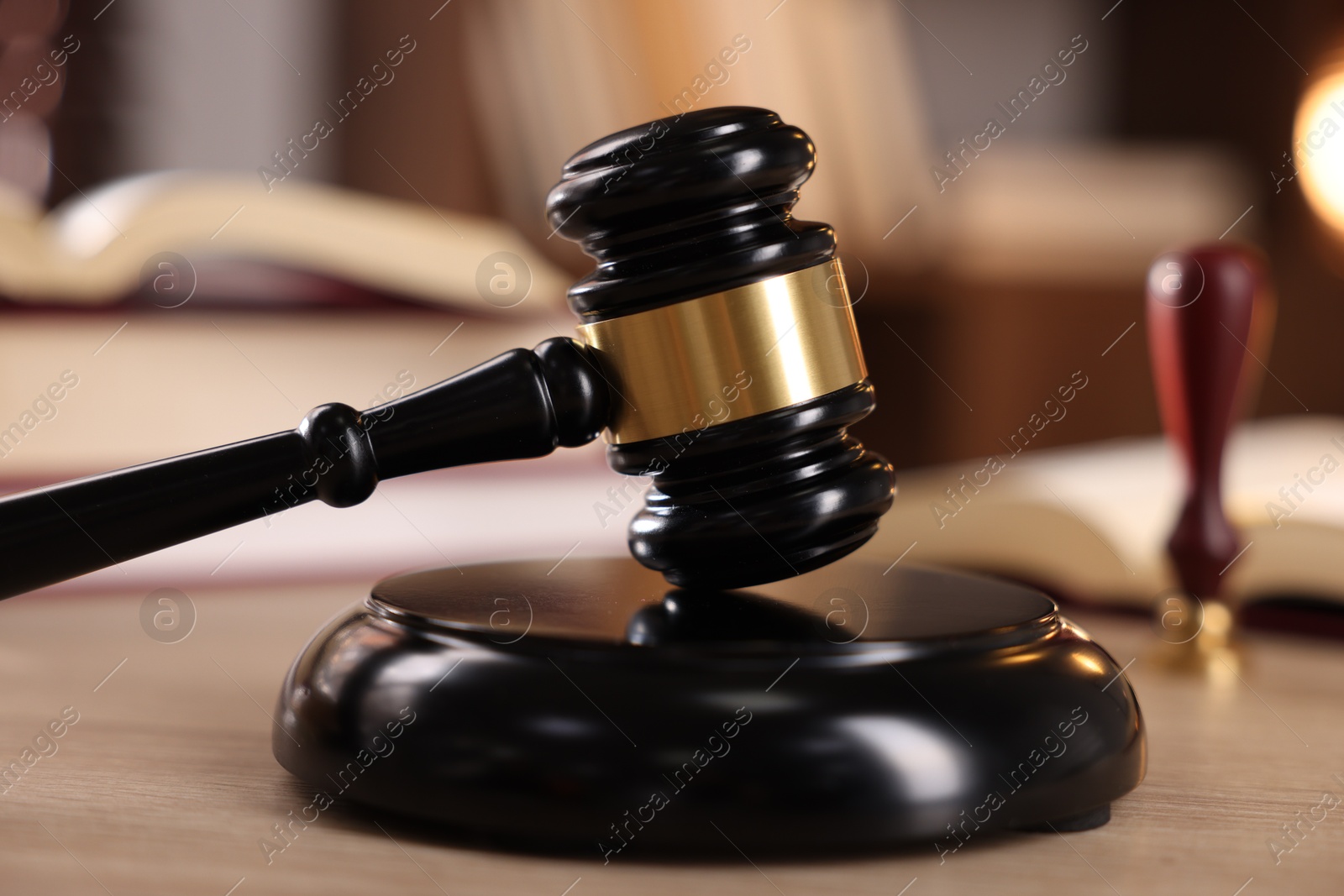 Photo of Judge's gavel and books on wooden table indoors, selective focus