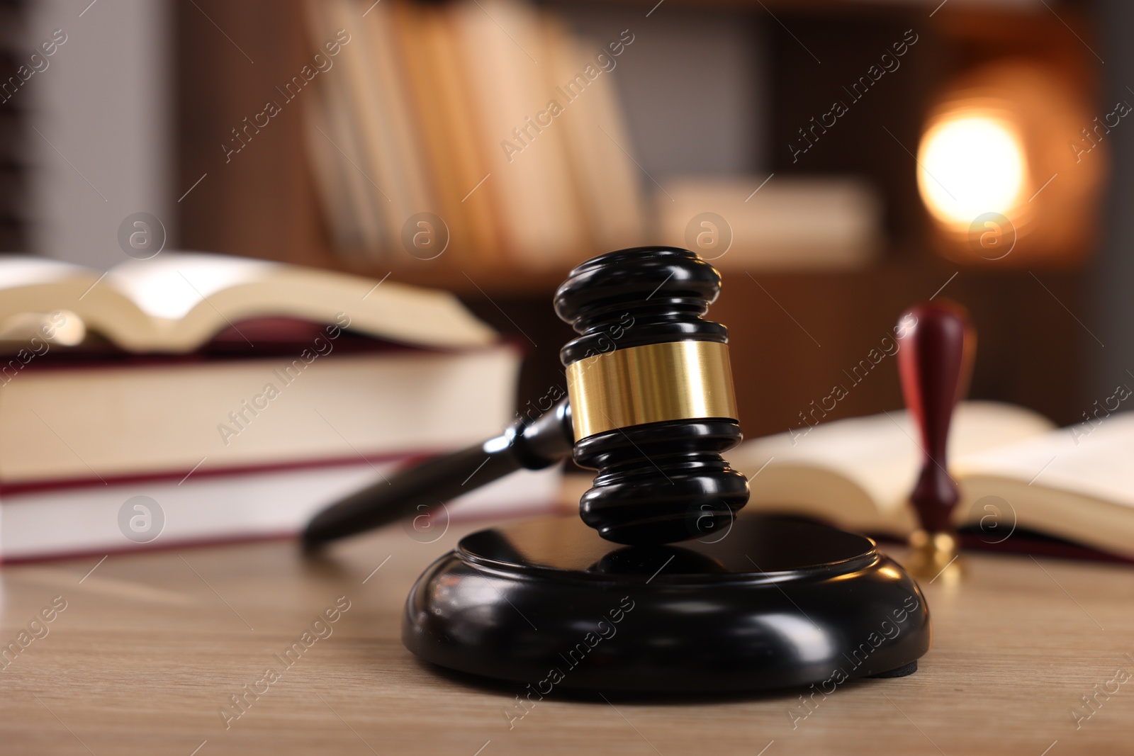 Photo of Judge's gavel and books on wooden table indoors, selective focus