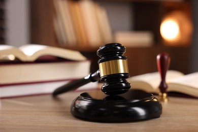 Photo of Judge's gavel and books on wooden table indoors, selective focus