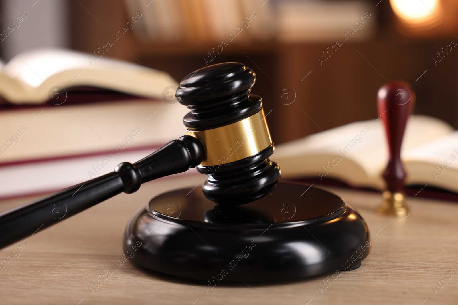 Photo of Judge's gavel and books on wooden table indoors, selective focus