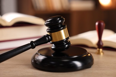 Photo of Judge's gavel and books on wooden table indoors, selective focus