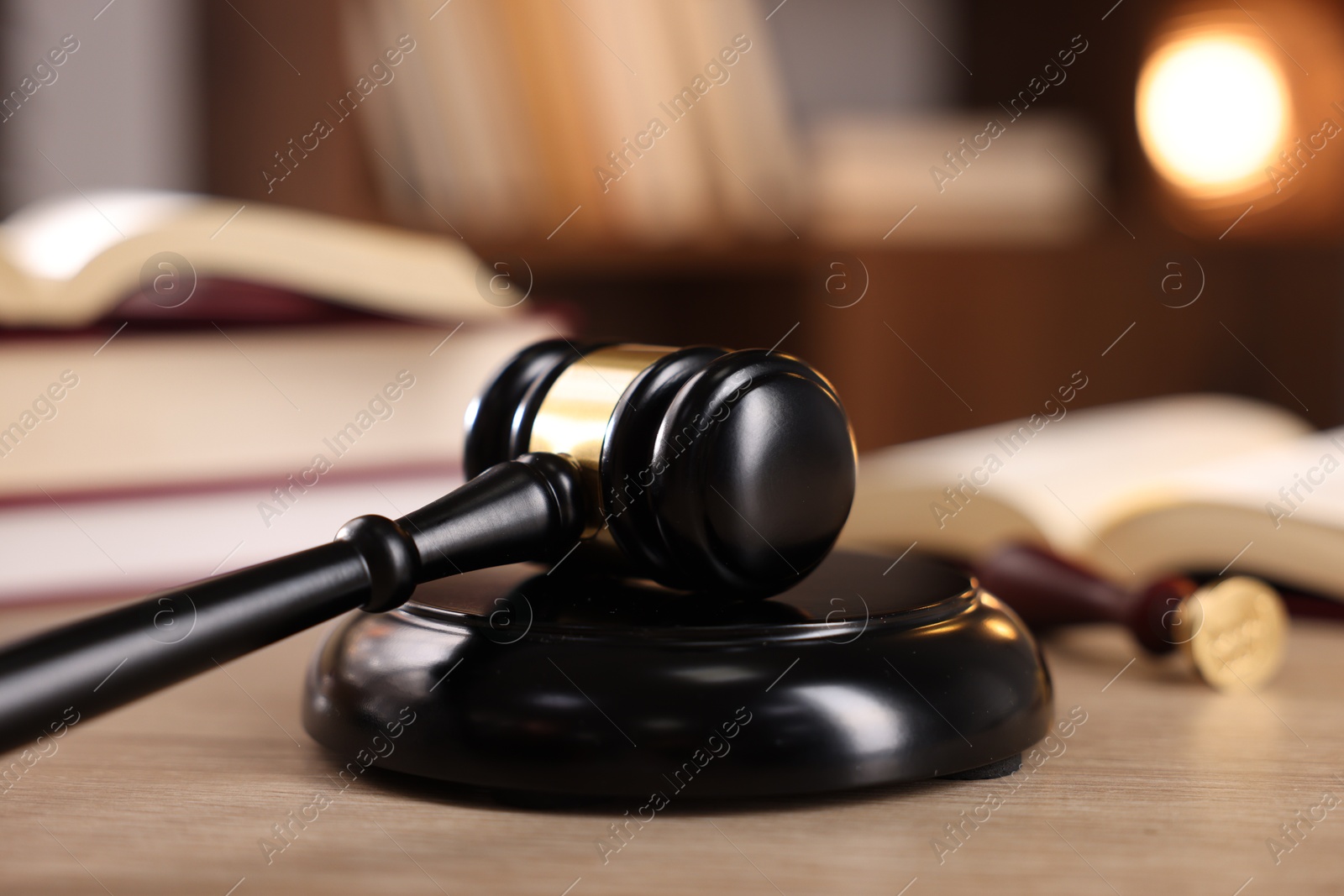 Photo of Judge's gavel and books on wooden table indoors, selective focus