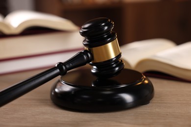 Photo of Judge's gavel and books on wooden table indoors, selective focus