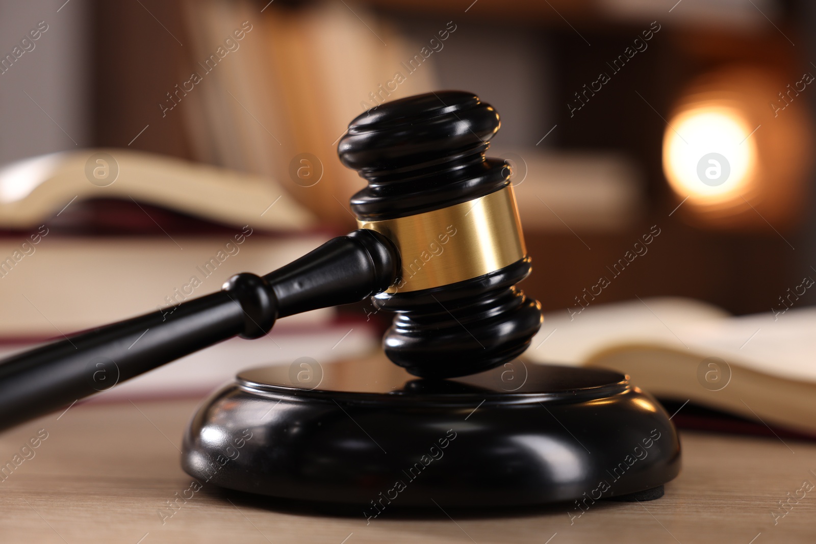 Photo of Judge's gavel and books on wooden table indoors, selective focus