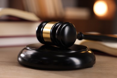 Photo of Judge's gavel and books on wooden table indoors, selective focus