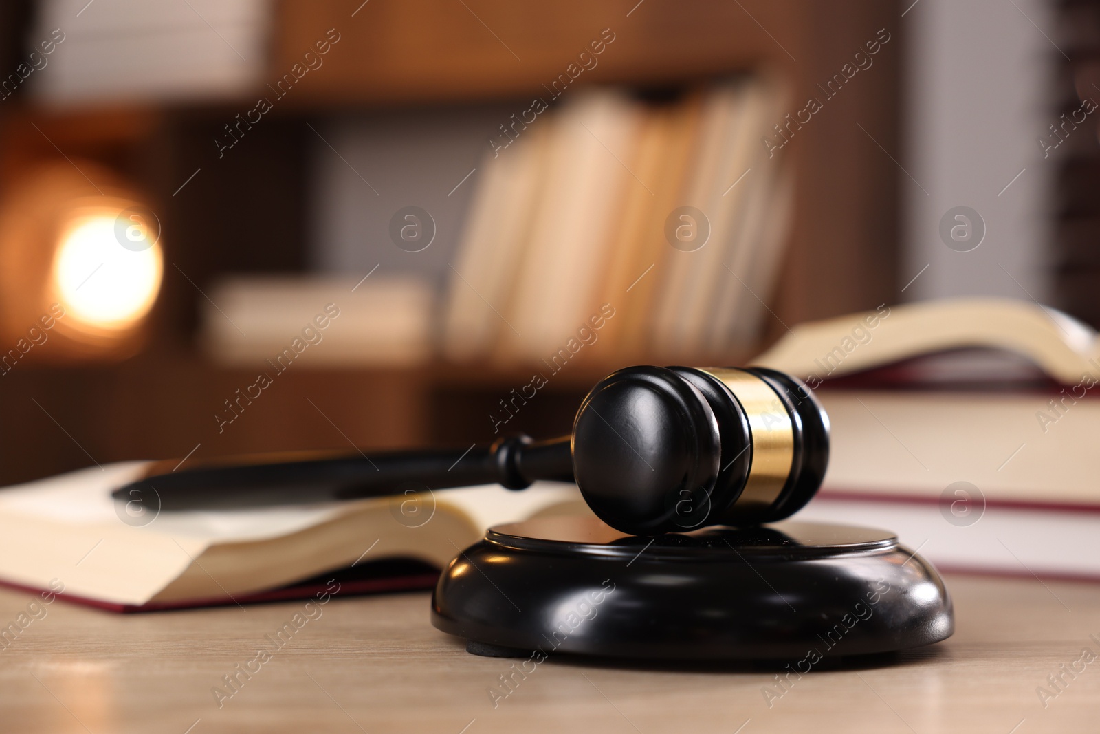 Photo of Judge's gavel and books on wooden table indoors, selective focus