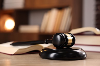 Photo of Judge's gavel and books on wooden table indoors, selective focus