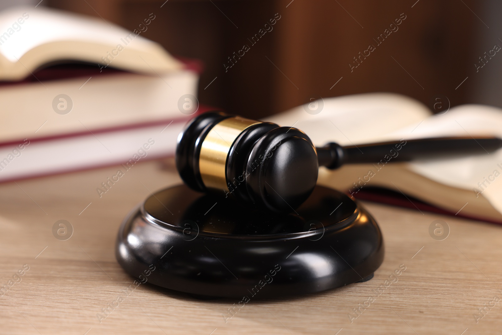 Photo of Judge's gavel and books on wooden table indoors, selective focus