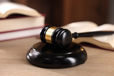 Photo of Judge's gavel and books on wooden table indoors, selective focus