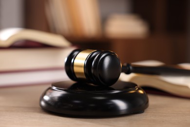 Photo of Judge's gavel and books on wooden table indoors, selective focus