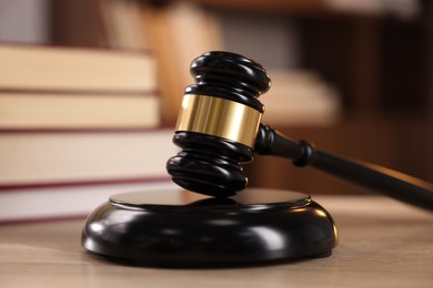 Photo of Judge's gavel and books on wooden table indoors, selective focus
