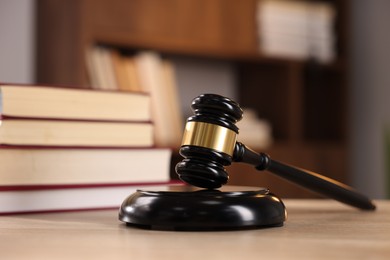 Photo of Judge's gavel and books on wooden table indoors, selective focus