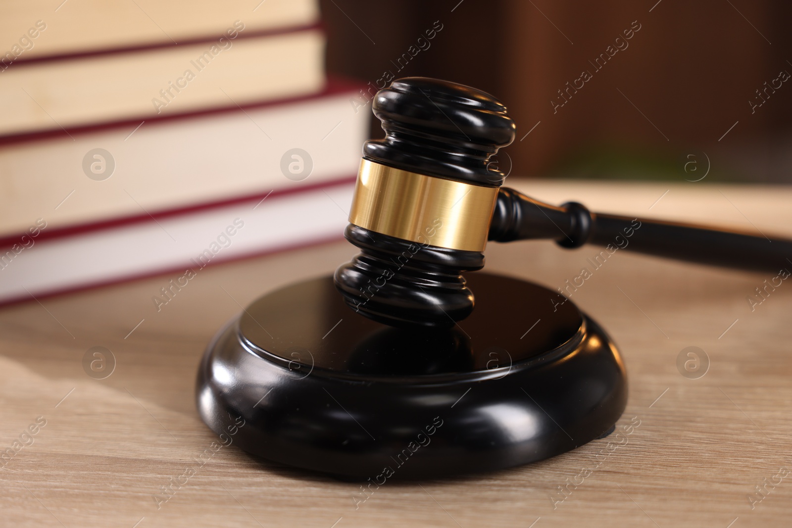 Photo of Judge's gavel and books on wooden table indoors, selective focus