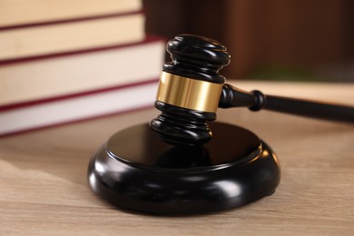 Photo of Judge's gavel and books on wooden table indoors, selective focus