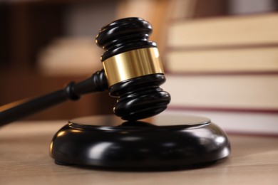 Photo of Judge's gavel and books on wooden table indoors, selective focus