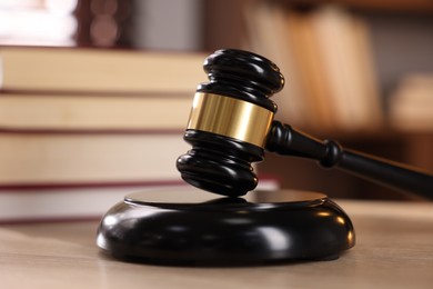 Photo of Judge's gavel and books on wooden table indoors, selective focus