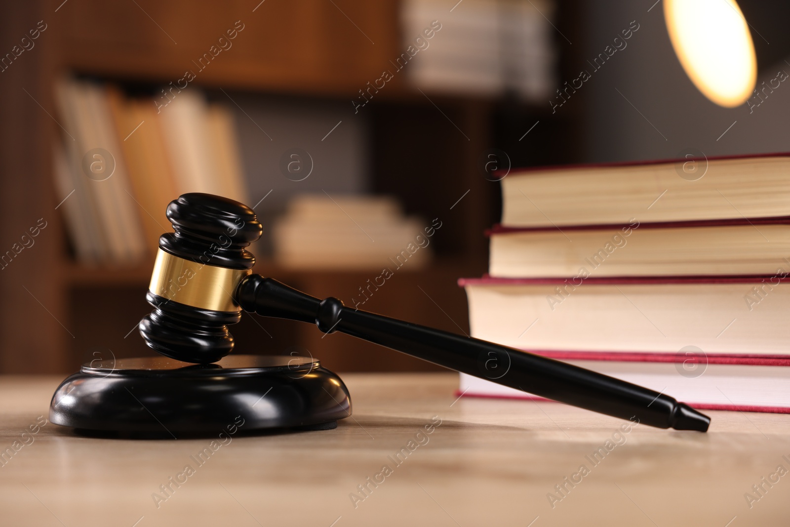 Photo of Judge's gavel and books on wooden table indoors, selective focus