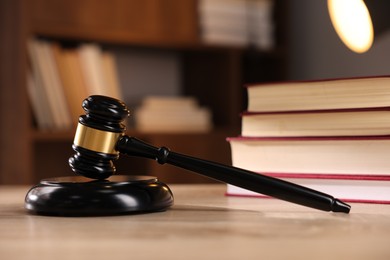 Photo of Judge's gavel and books on wooden table indoors, selective focus