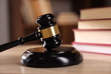 Photo of Judge's gavel and books on wooden table indoors, selective focus