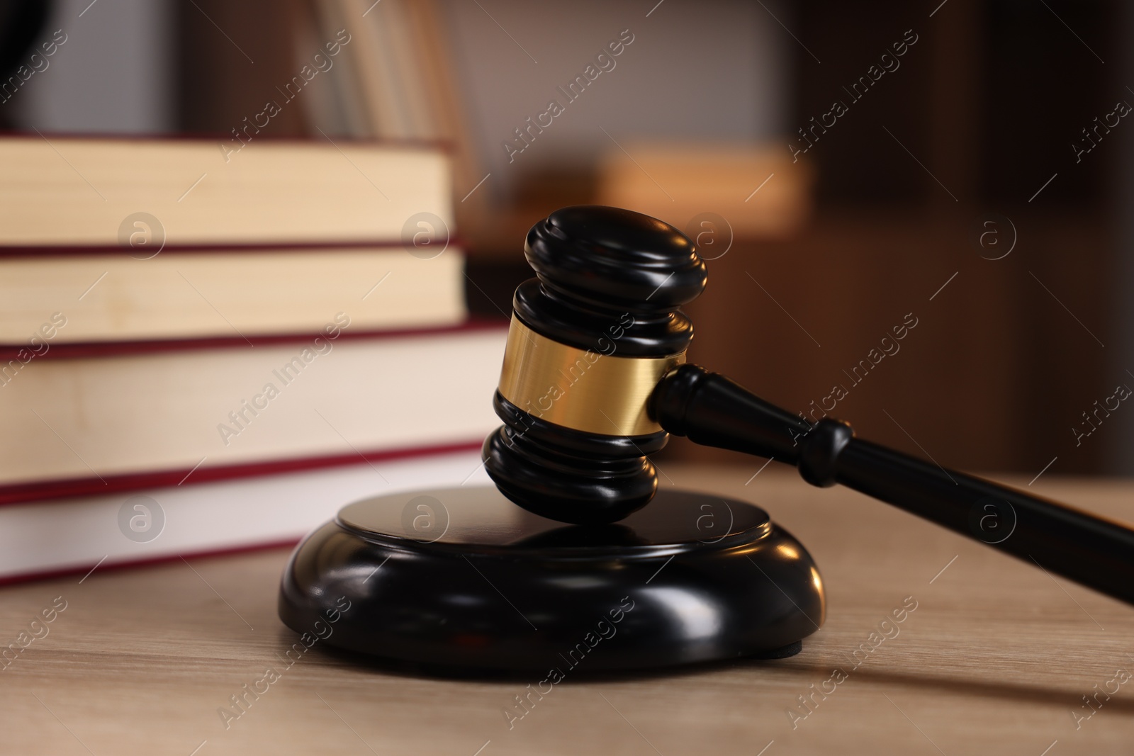 Photo of Judge's gavel and books on wooden table indoors, selective focus