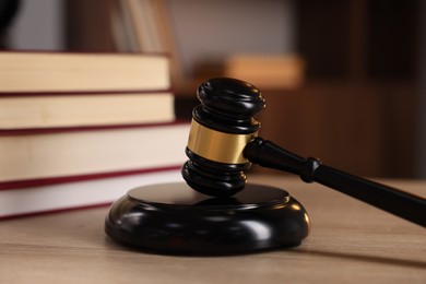 Photo of Judge's gavel and books on wooden table indoors, selective focus